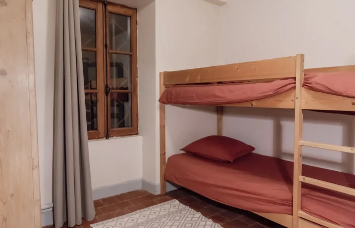Chambre Kids du gîte Le Presbytère au Parc de Lesseps — lits superposés en bois, linge terracotta, tomettes, fenêtre ancienne, chambre enfants pour séjour famille ou week-end mariage en Berry Indre