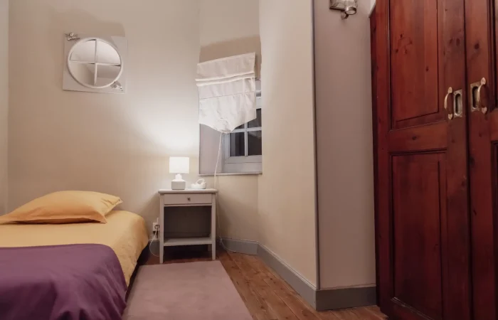 Chambre individuelle du gîte Le Presbytère au Parc de Lesseps — lit simple, armoire en bois, ambiance chaleureuse, idéale pour invité ou accompagnant lors d'un week-end mariage ou séjour groupe en Indre
