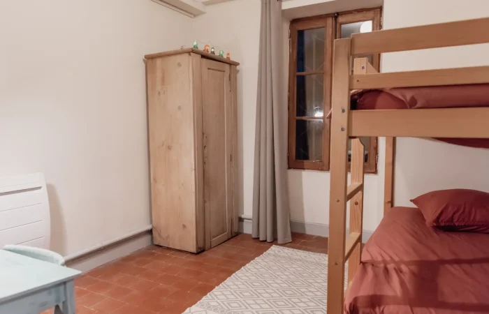 Chambre enfants du gîte Le Presbytère — lits superposés, armoire en pin brut, guirlande lumineuse, tomettes, hébergement famille pour week-end mariage ou séjour groupe en Indre 36