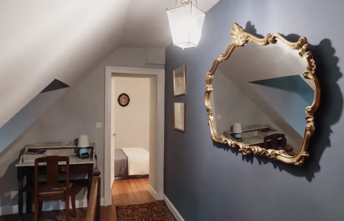Couloir de la suite Charles au gîte Le Presbytère — mur bleu ardoise, miroir doré baroque, lanterne ancienne, détail de caractère pour séjour de charme en Berry