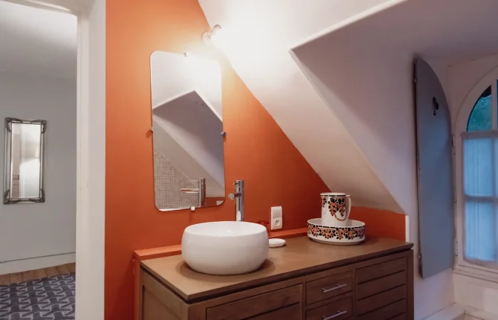 Salle de bain de la suite Charles au Parc de Lesseps — vasque ronde sur meuble teck, mur terracotta, fenêtre en arche, salle d'eau privative pour hébergement de caractère en Indre