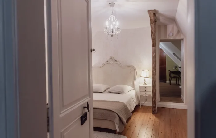 Suite Diane du gîte Le Presbytère au Parc de Lesseps — lit baroque blanc, lustre en cristal, parquet bois, hébergement de charme pour séjour romantique ou week-end mariage en Berry