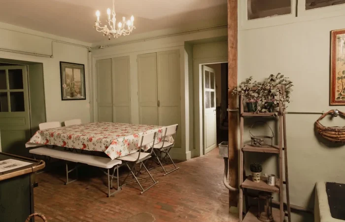 Salle à manger du gîte Le Presbytère au Parc de Lesseps — grande table, sol en tomettes, lustre ancien, ambiance maison de famille pour séjour ou week-end de mariage en Berry