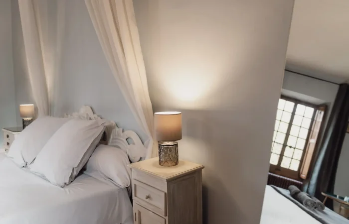 Détail chevet et lampe de la suite Gaïa avec baldaquin et fenêtres anciennes, Château de Planches Parc de Lesseps