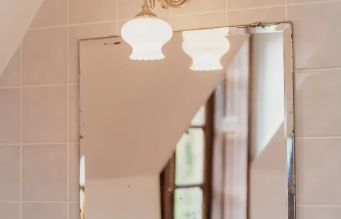 Miroir ancien et applique dorée dans la salle de bain de la suite Gaïa, Château de Planches