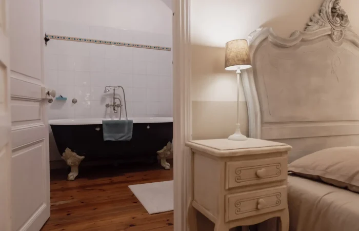 Suite Artemis du gîte Le Presbytère au Parc de Lesseps — baignoire ancienne sur pieds noirs, tête de lit baroque sculptée, parquet pin, chambre romantique pour séjour ou nuit de noces en Berry