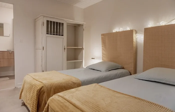 Suite twin Ezhesekis du gîte Le Presbytère au Parc de Lesseps — deux lits simples, têtes de lit cannage, guirlande lumineuse, chambre twin pour hébergement groupe ou week-end mariage en Berry Indre
